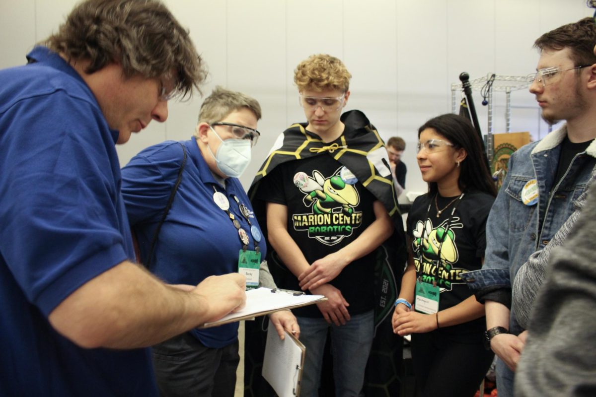 Seniors, Mackenzie Thomas, Risecen McGinnis, and Nathan Druschel, speak with judges about the engineering behind their 2024 completion bot.